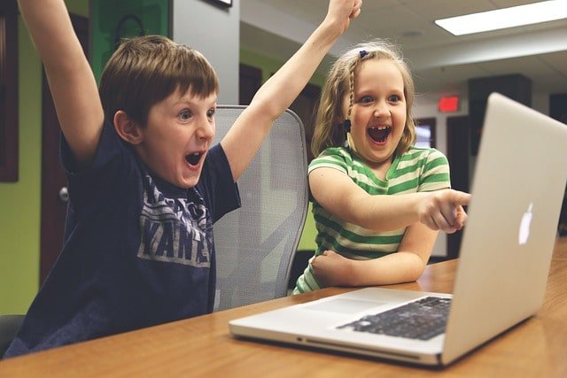 Por qué es importante contratar una agencia de marketing especializada en tu sector. Niño y niña frente a una laptop felices y celebrando un encuentro en Google