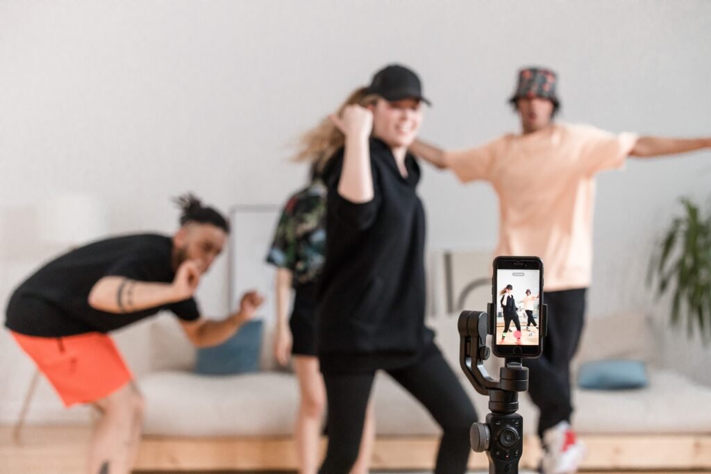 grupo de 4 jovenes compuestos por chicos y chicas haciendo una coreografía delante de su teléfono móvil para un video para las redes sociales